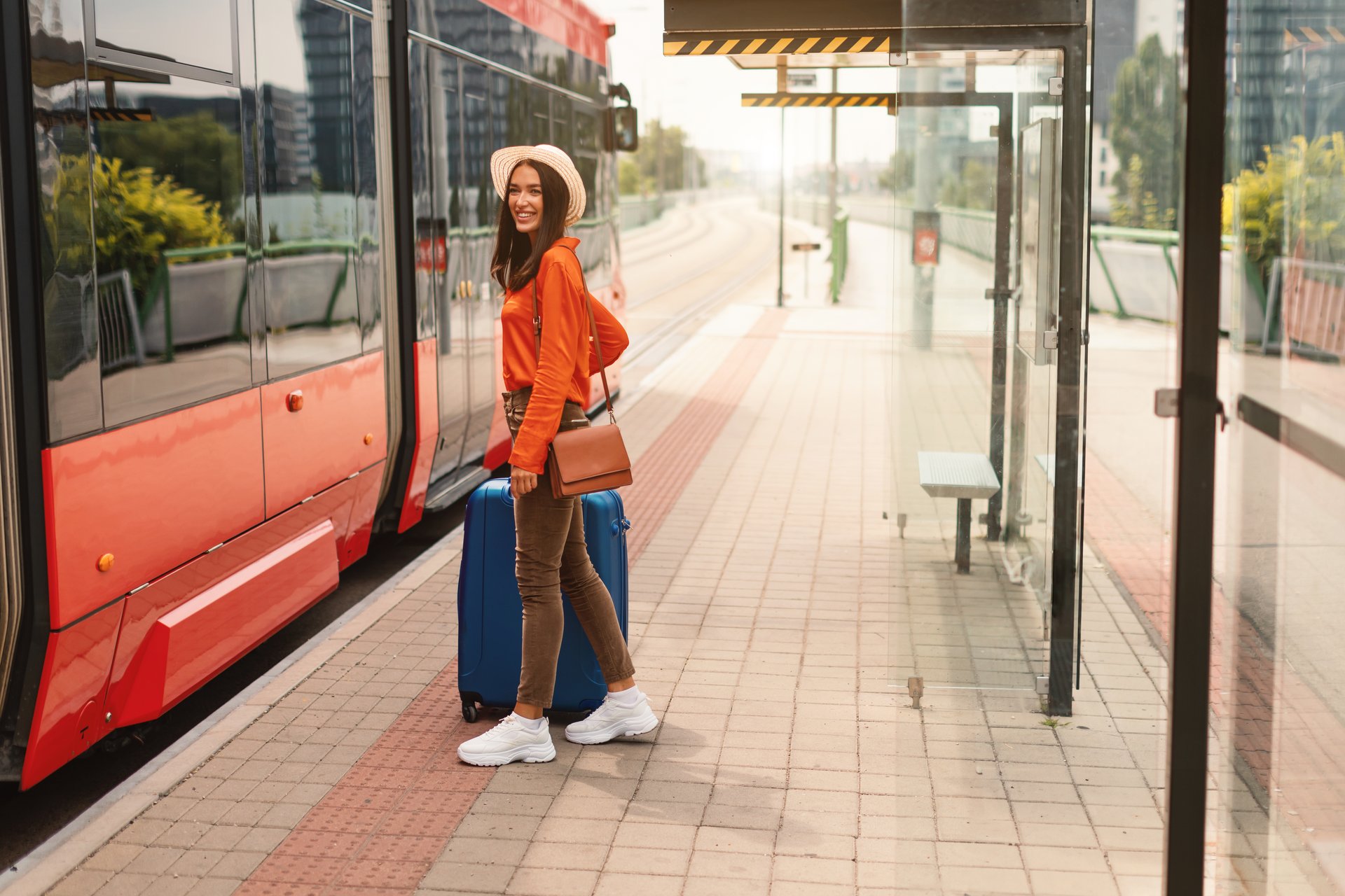 Studentka z walizką wsiada do tramwaju na przystanku